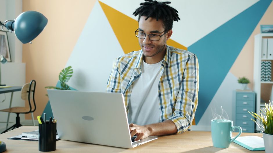 A marketing expert sits in a stylish, modern home, working diligently on a laptop to manage the online strategy for a property sale.