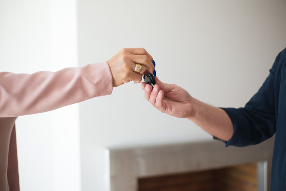 A clean, professional close-up of one person's hands giving a set of house keys to another, representing a successful real estate transaction.